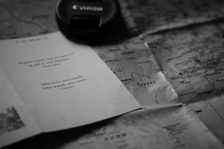 FamousParentingMomlife A black and white image of an inspirational travel quote alongside a map and camera lens cap.