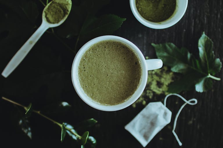 Bin Matcha A calming overhead shot of a matcha latte surrounded by leaves and matcha powder for a natural touch.