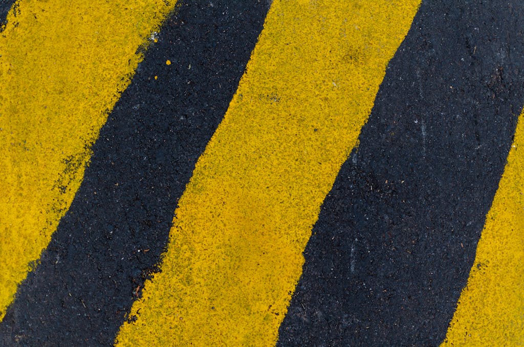 Whatsontech  A high-angle close-up of yellow and black road markings on asphalt surface.