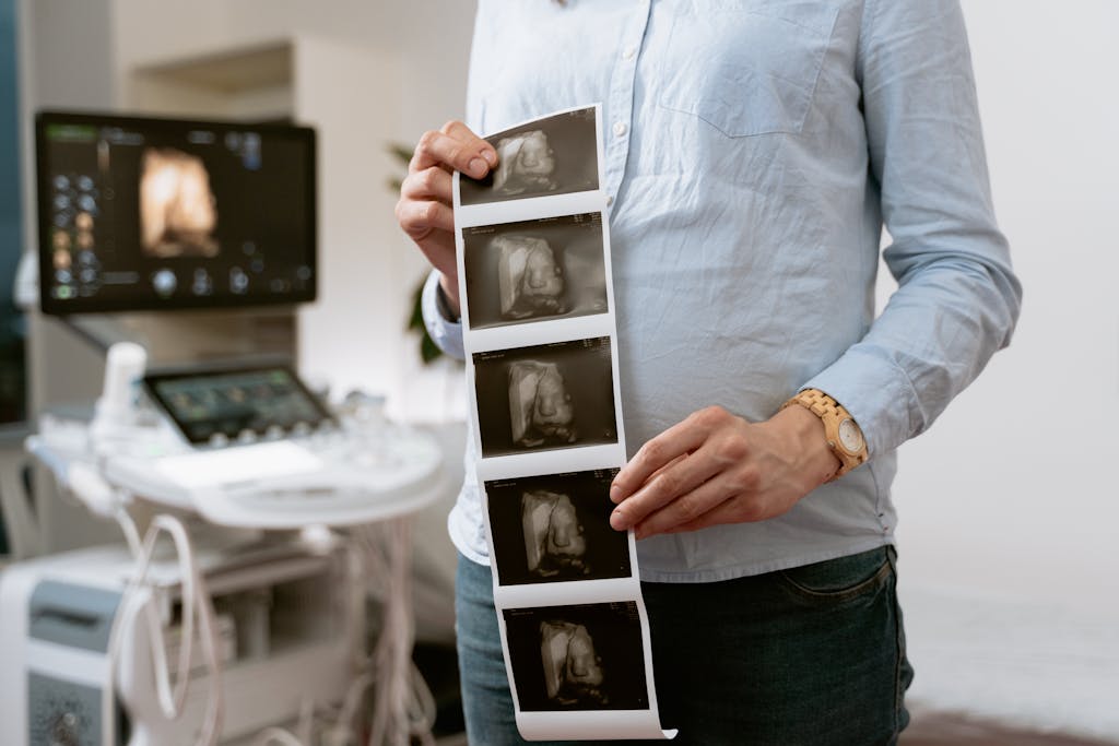 Digital Media Tumbons A person holding ultrasound images in a medical clinic, showcasing pregnancy monitoring.