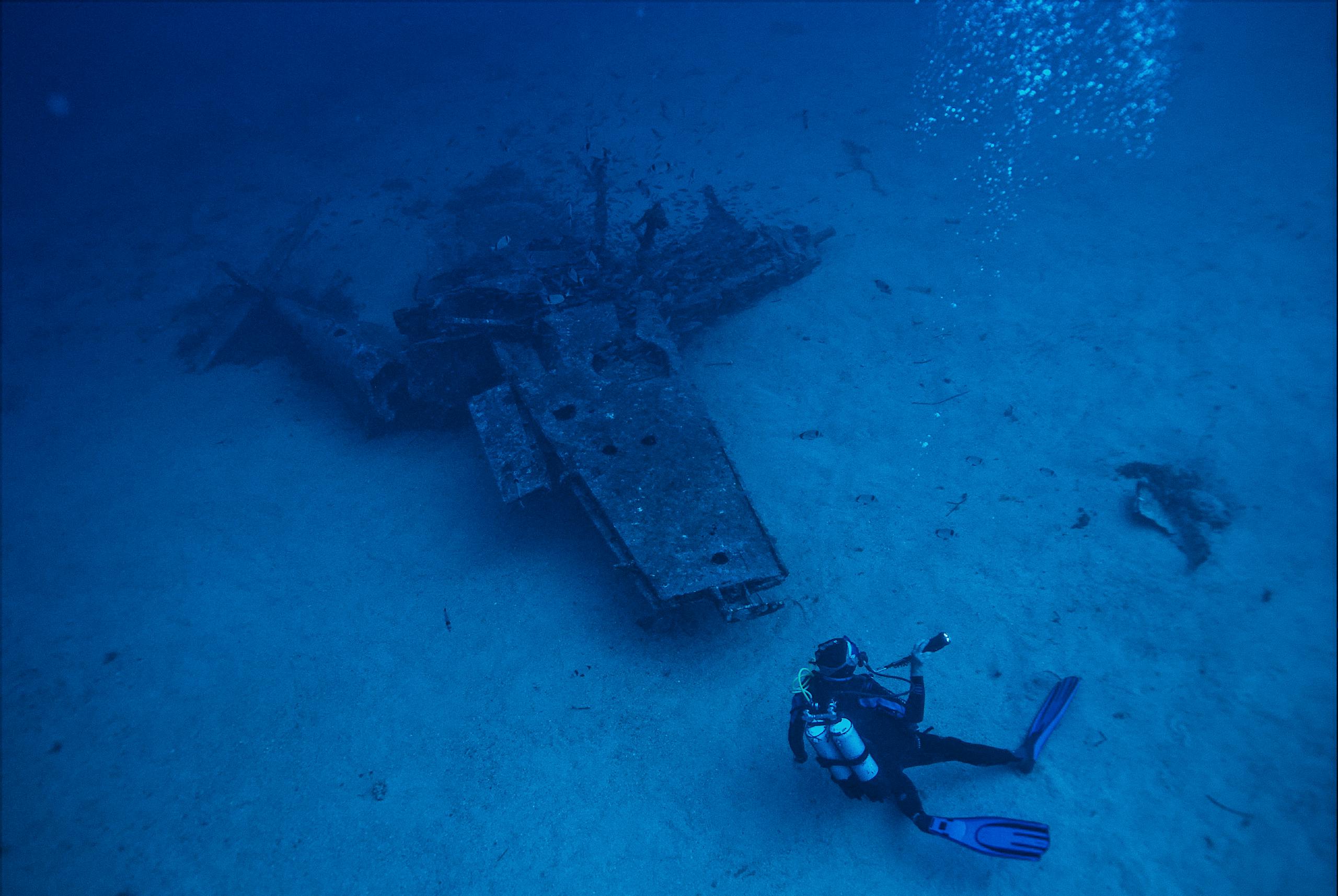 Newstook A scuba diver explores a submerged shipwreck deep underwater, capturing adventure and exploration.