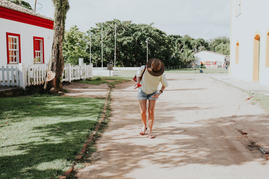 Juntos Seguros A woman in casual attire walks down a sunny street in Porto Seguro, Bahia, Brazil.