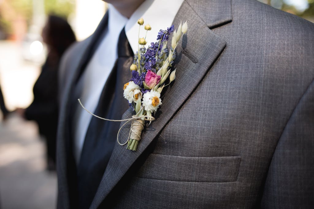 Blazertje Close-up of an elegant groom wearing a designer suit and floral boutonniere during a wedding ceremony.