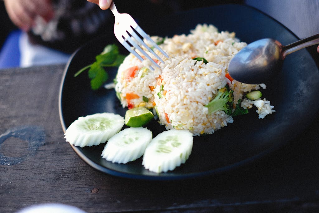 Dampfreis Close-up of fried rice served with sliced cucumbers, perfect for a healthy meal.