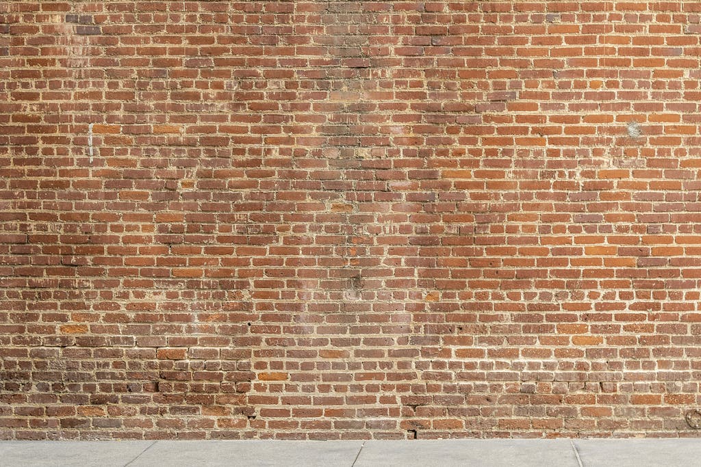 SocialMediaGirl Detailed image of a textured red brick wall with a concrete base, ideal for architectural and design backgrounds.