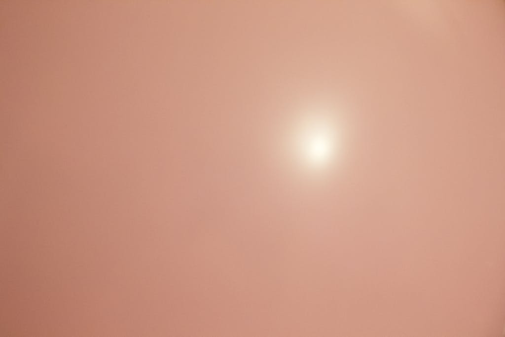 Emfyteymata Dreamy soft peach pink background with bright sun, ideal for wallpapers.