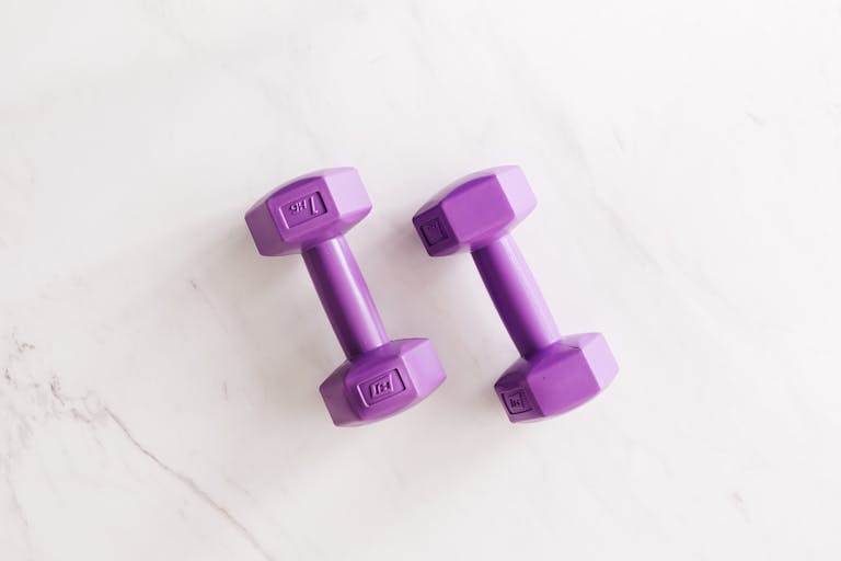 Trios 5 Invisalign Submission Overhead shot of two purple dumbbells on a white marble surface.