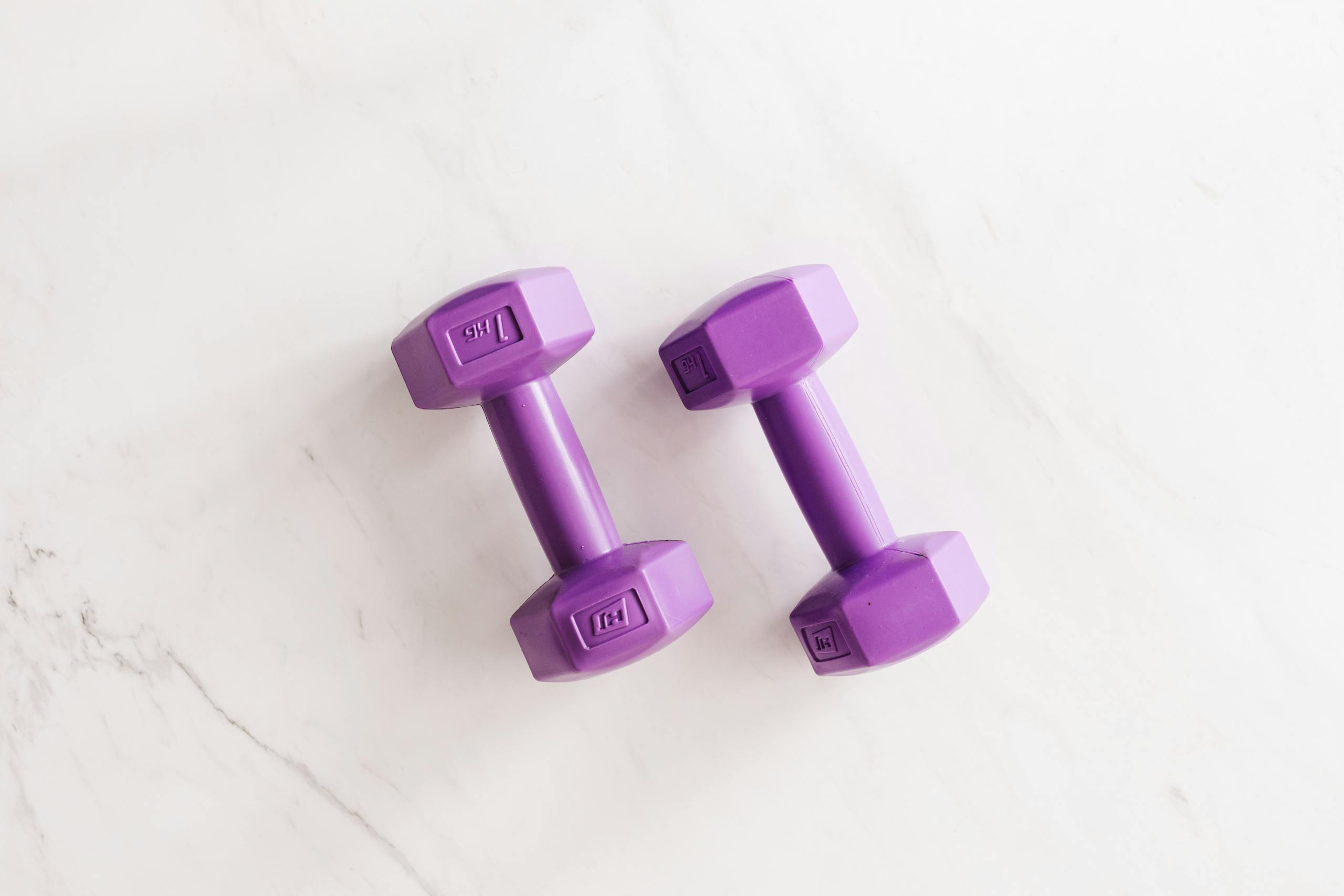 Trios 5 Invisalign Submission Overhead shot of two purple dumbbells on a white marble surface.
