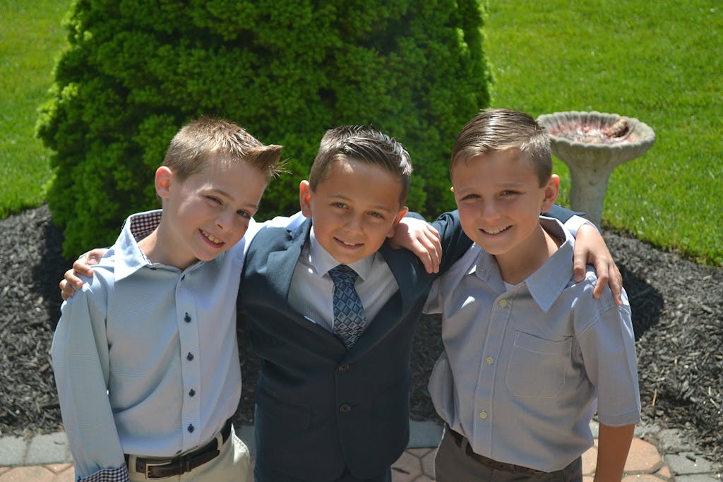 Entrepreneur Break Three boys in formal shirts smiling together outdoors in a sunny garden.
