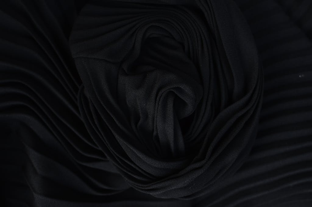Uitly.com Top view of abstract background representing wavy creased black silk fabric in twilight